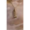 Collier pendentif poisson doré sur fond flou.
