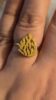 Bague dorée en forme de flamme sur doigt.
