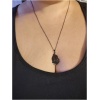 Collier avec pendentif noir sur fond de peau.