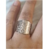Bague argentée texturée sur un doigt.