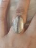 Bague argentée avec motif structuré sur doigt.