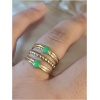 Bague en or avec pierres vertes sur doigt.