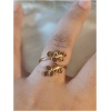 Bague dorée avec feuilles sur un doigt.