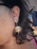 Boucles d'oreilles dorées en forme de soleil.
