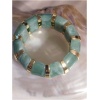Bracelet vert et doré sur fond nacré.