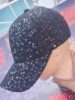 Casquette noire à paillettes sur mannequin en plastique.